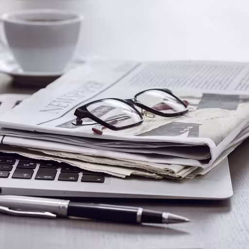 Eine Brille auf einer Zeitung, die auf einem Laptop liegt